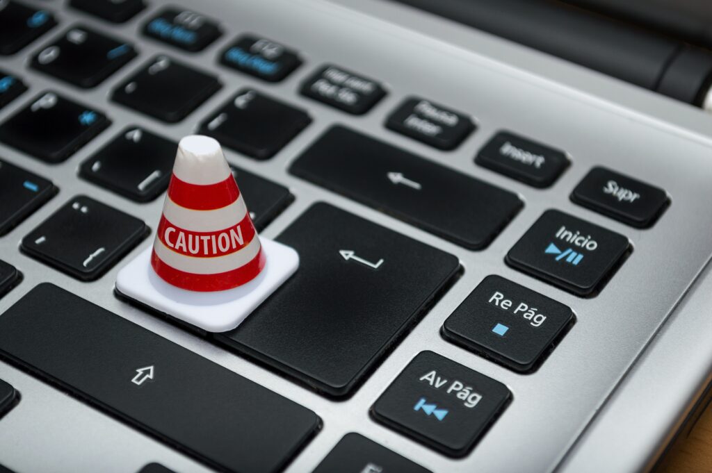 A red and white cone sits on the keyboard of a laptop.