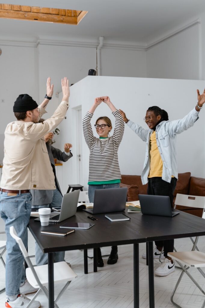A group of people raising their hands in an office.