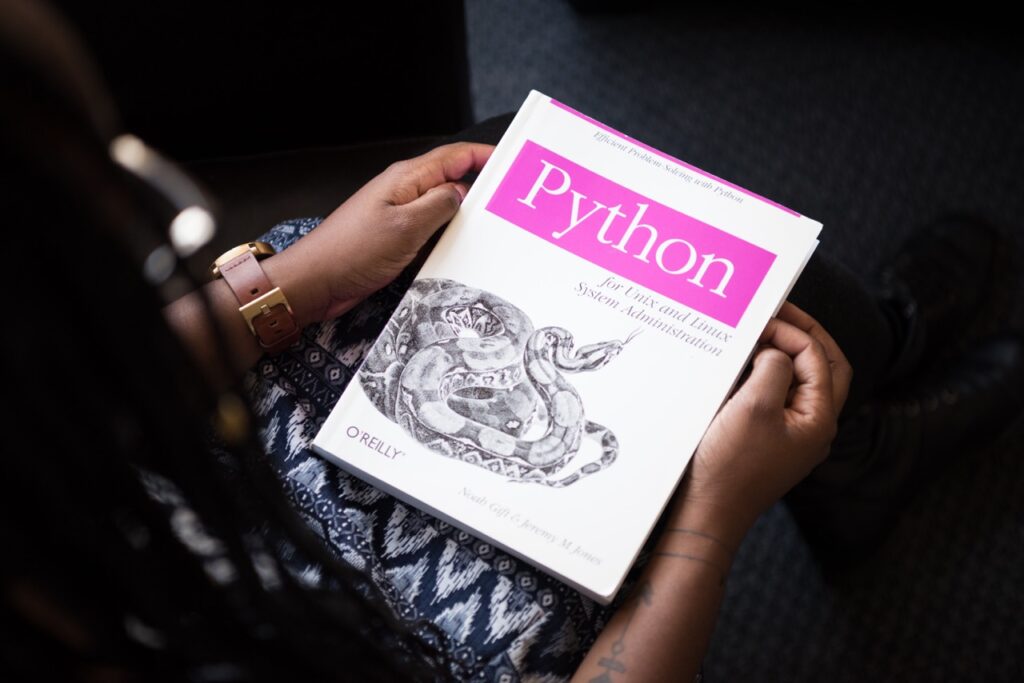 A woman holding a book about python.