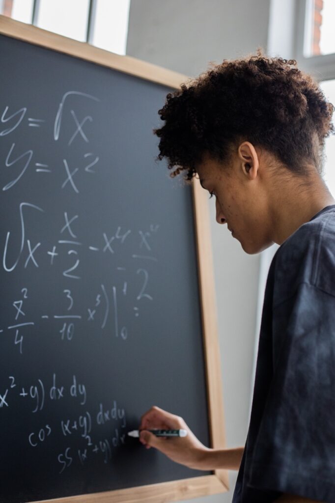 A young man writing on a blackboard.
