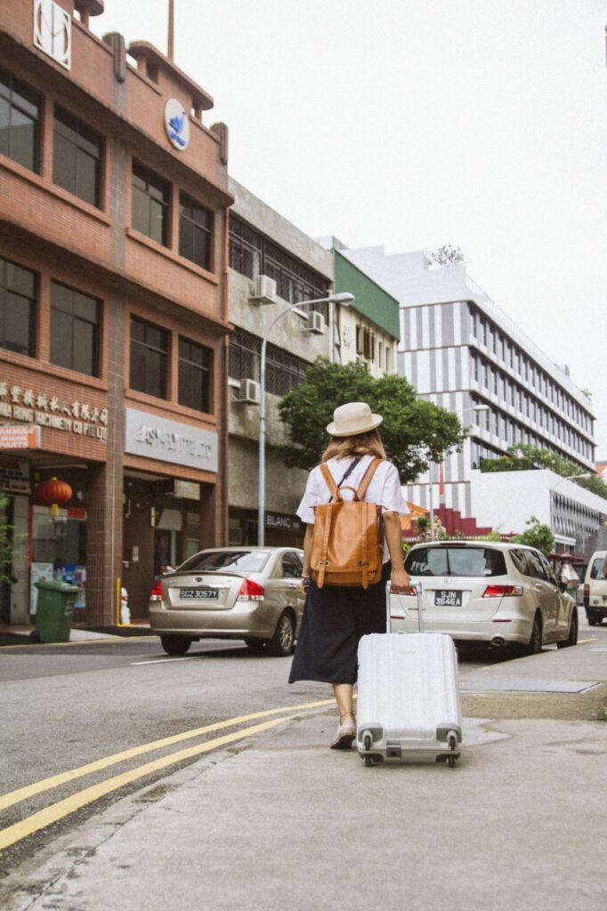 A woman walking down a street with a suitcase.