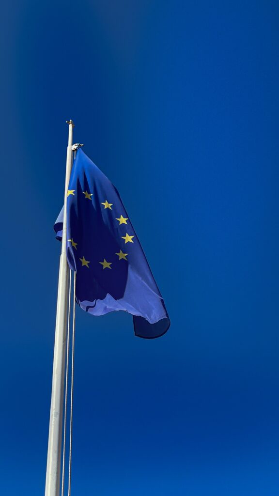 An eu flag flying in the wind against a blue sky.