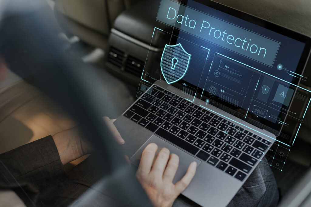 A man is using a laptop in the back seat of a car to comply with GDPR.