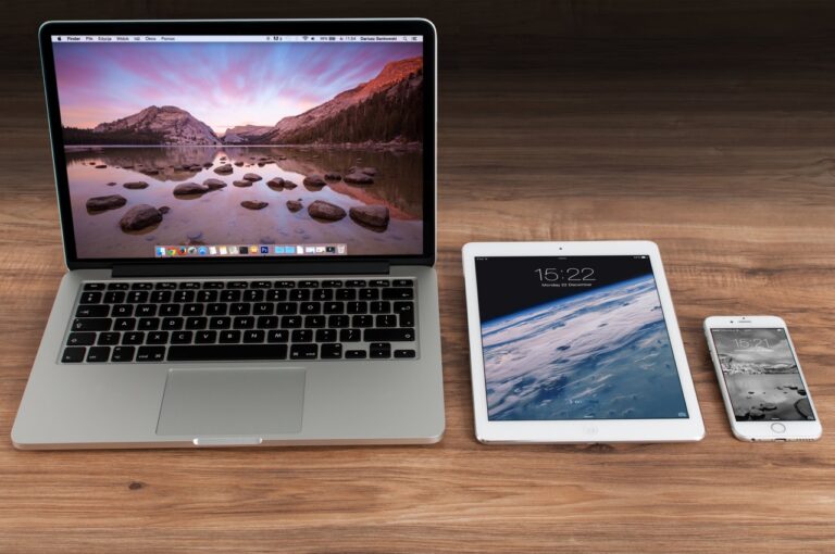 A laptop, tablet, and ipad on a wooden table are depicted in the image.
