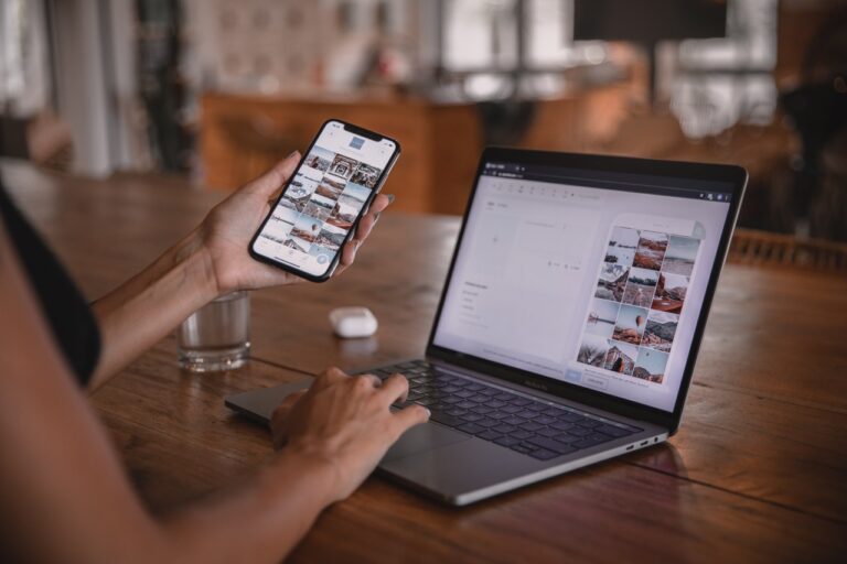 A woman multitasking with a phone and laptop on a wooden table.